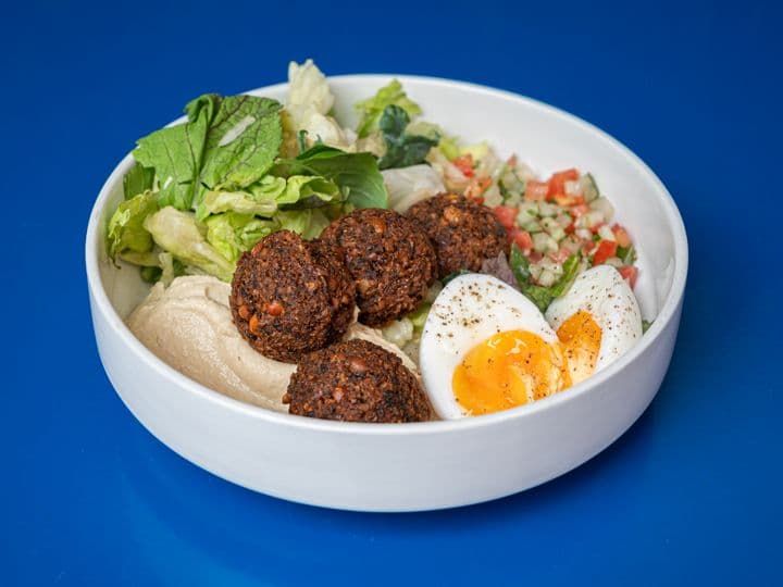 Imagen de Bowl de falafel con verdes, ensalada israelí, hummus y huevo